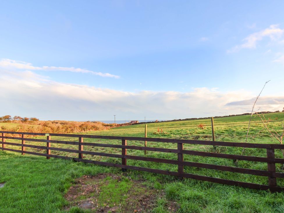 A view of a fenced grassland under a partly cloudy sky at Swift Cabin in Scarborough