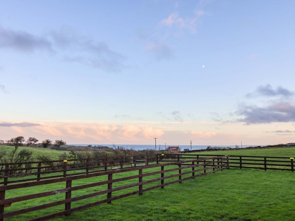 An open field with a wooden fence and distant hills at Swift Cabin in Scarborough