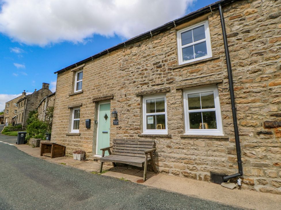 A stone cottage exterior with a bench outside at Wayside Farm Richmond
