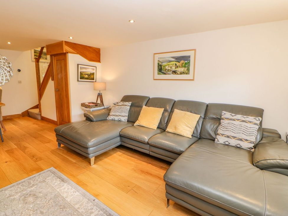 A living room with a grey sofa and wooden stairs at Wayside Farm Richmond