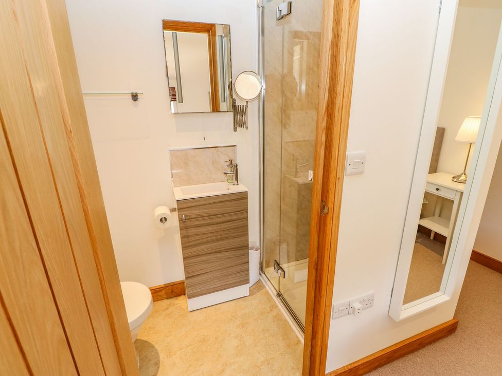 A bathroom with a shower, toilet, sink, and mirror at Wayside Farm Richmond