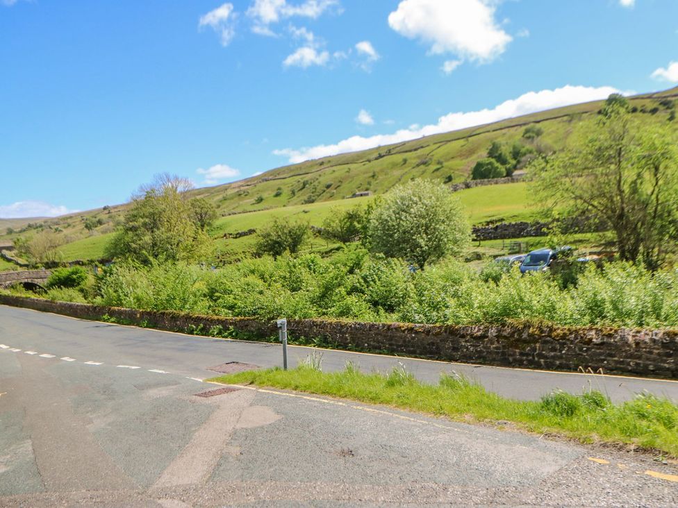 A view of a road with grassy hills and trees at Wayside Farm Richmond