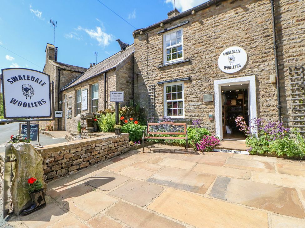 A shop exterior with a bench and flowers at Swaledale Woollens in Richmond