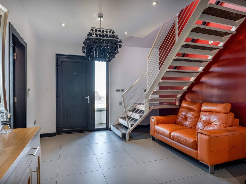 A hallway with a staircase and an orange sofa at Bellevue in 