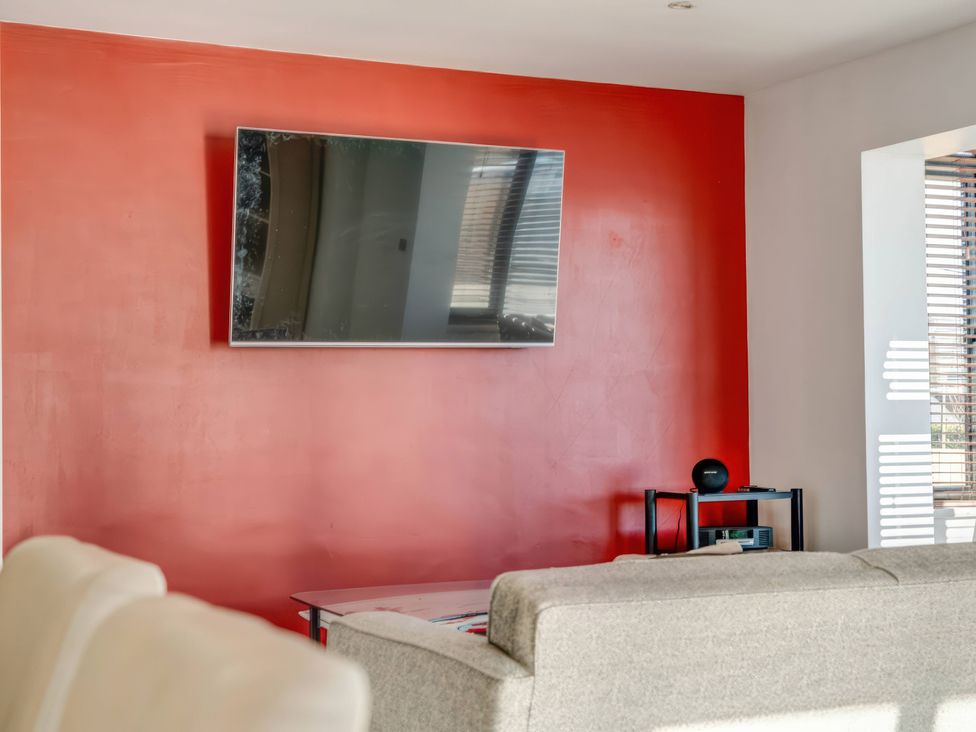 A living room with a television mounted on a red wall at Bellevue