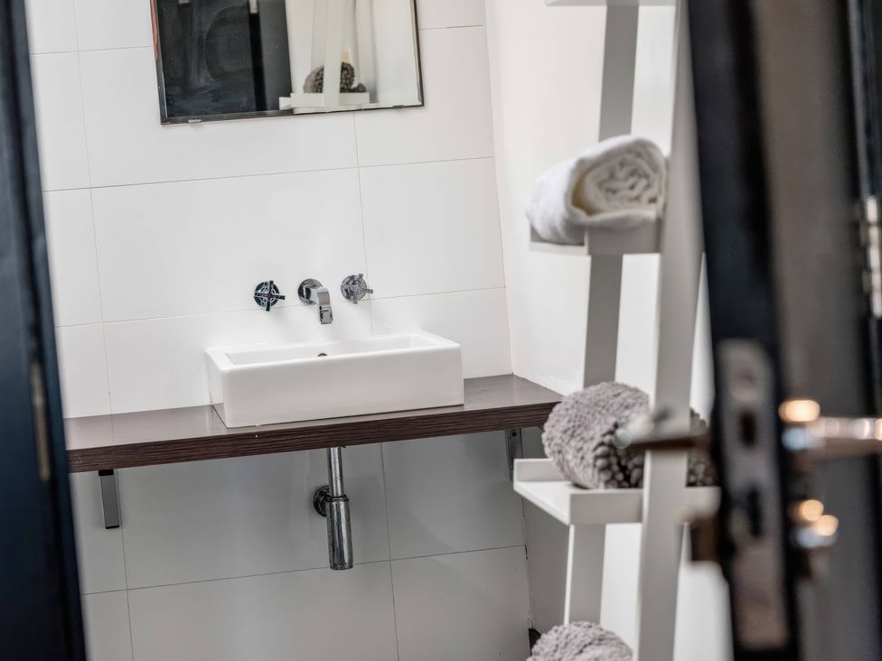 A bathroom with a sink and towels in a shelf at Bellevue