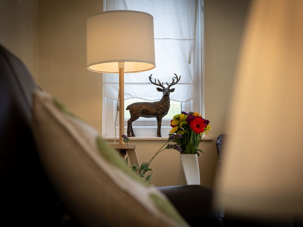 A living room with a lamp and a deer figurine at Oaks Lodge Cottage in Ambleside