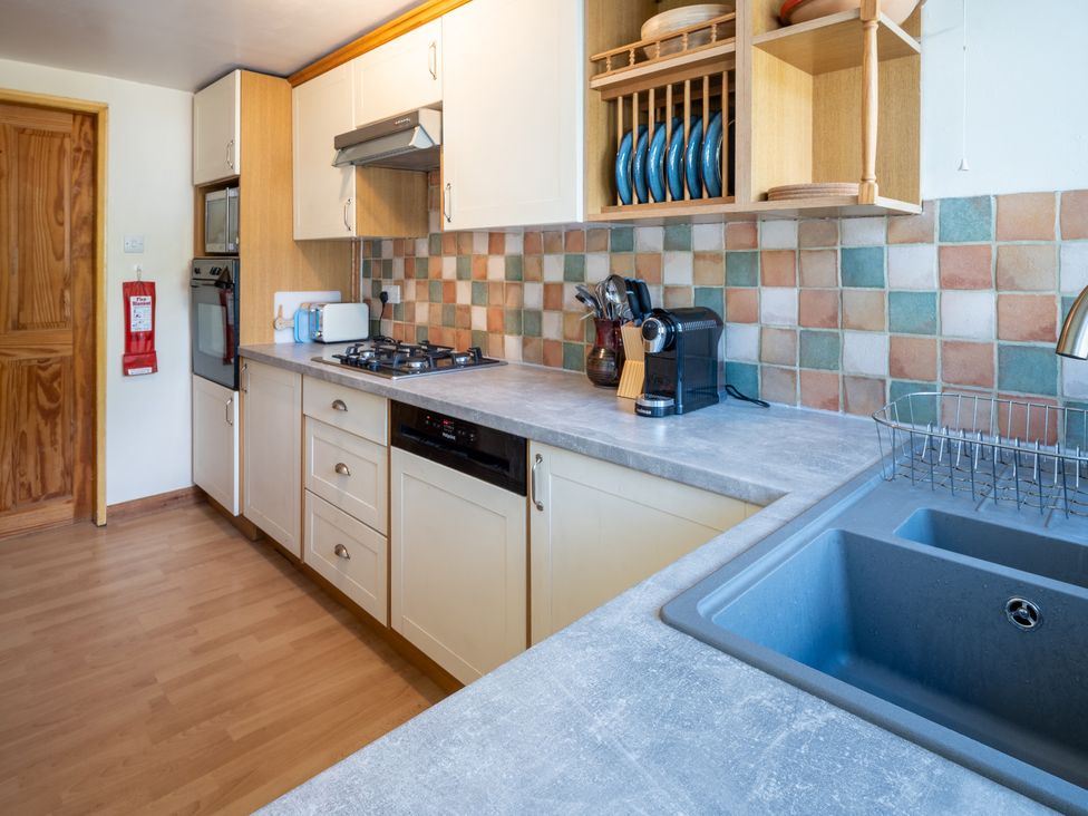 A kitchen with cabinets, sink, stove, and appliances at Oaks Lodge Cottage in Ambleside