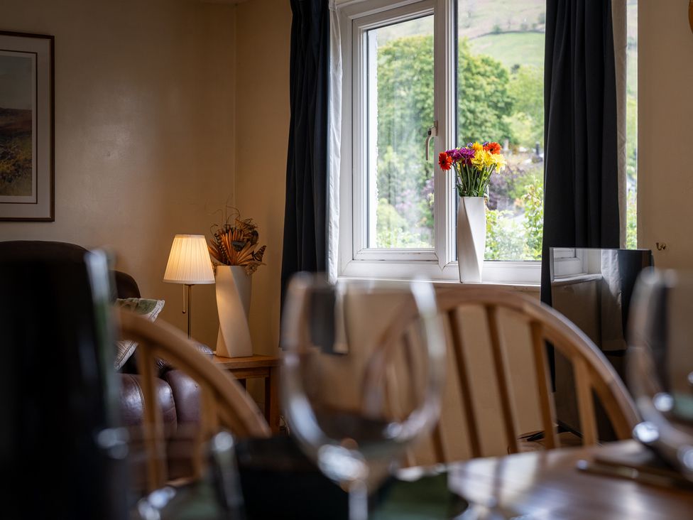 A living room with a window and flowers at Oaks Lodge Cottage in Ambleside
