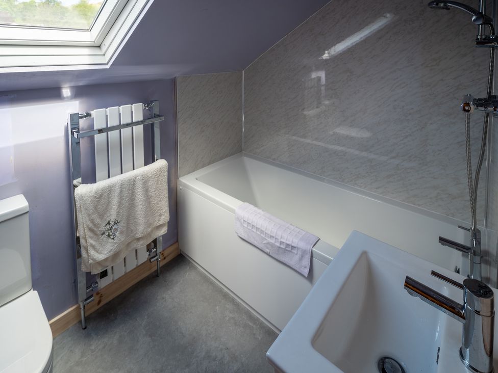 A bathroom with a bathtub, toilet, and hand basin at Oaks Lodge Cottage Ambleside