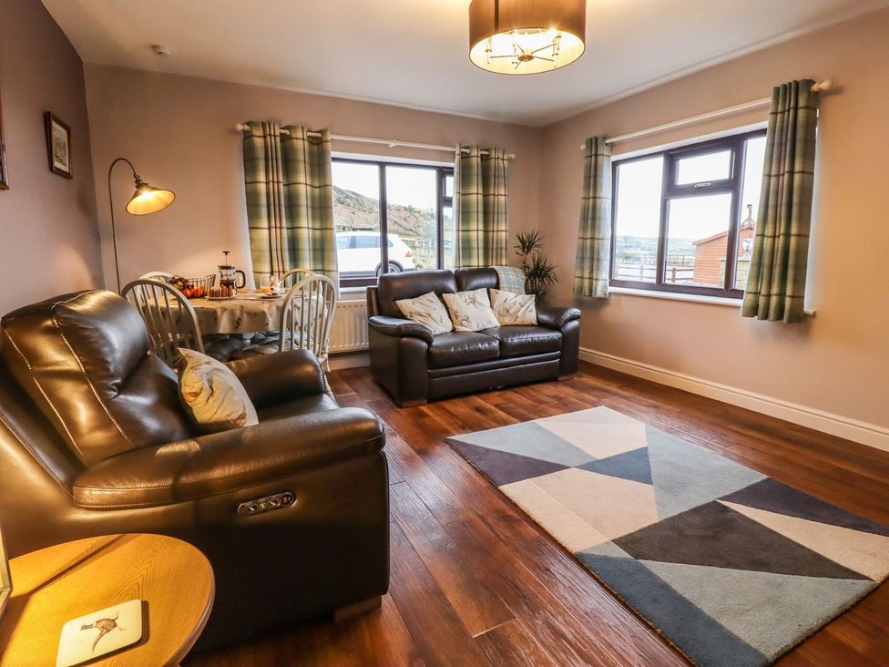 A living room with seating and a dining area at Baywood Cottage in Keighley