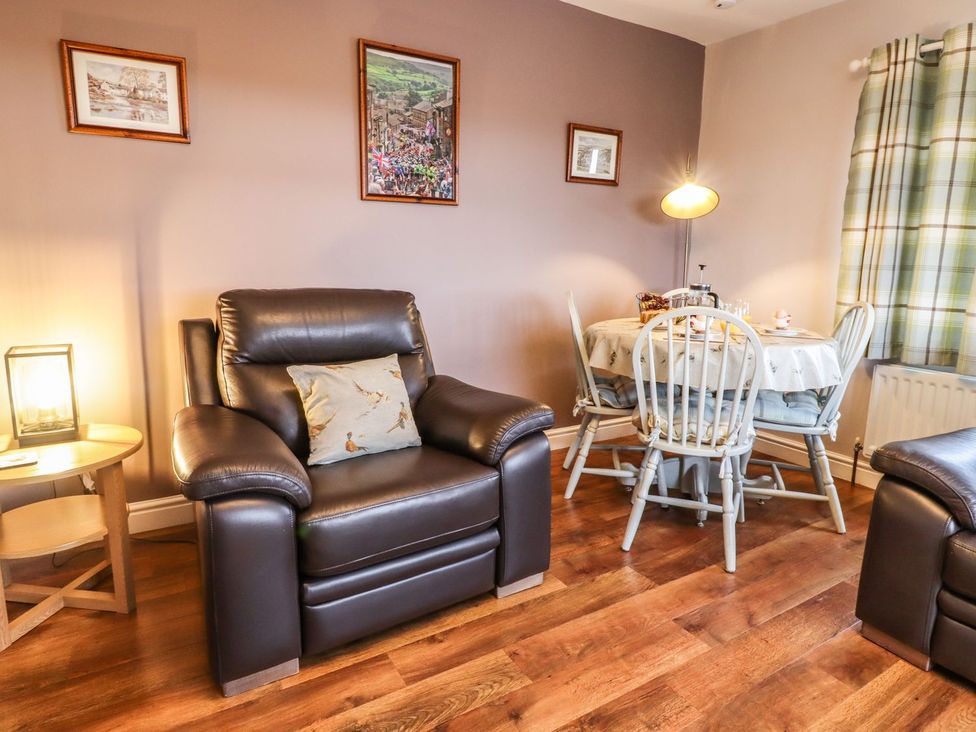 A living room with an armchair and dining table at Baywood Cottage in Keighley