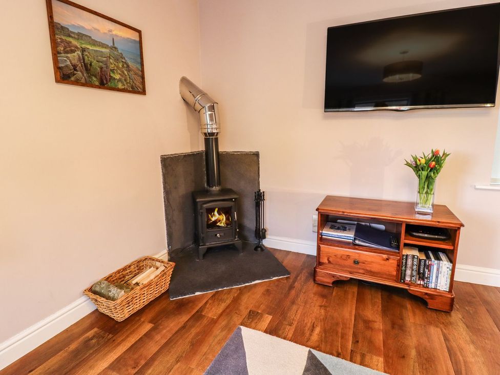 A living room with a stove and television at Baywood Cottage in Keighley
