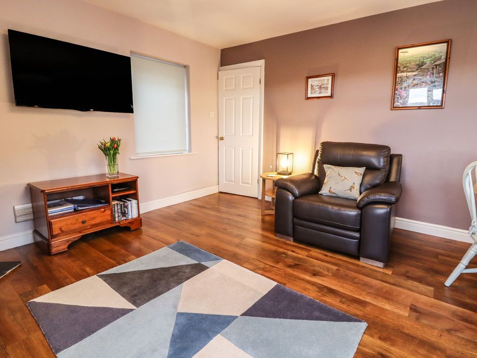 A living room with a television and an armchair at Baywood Cottage in Keighley