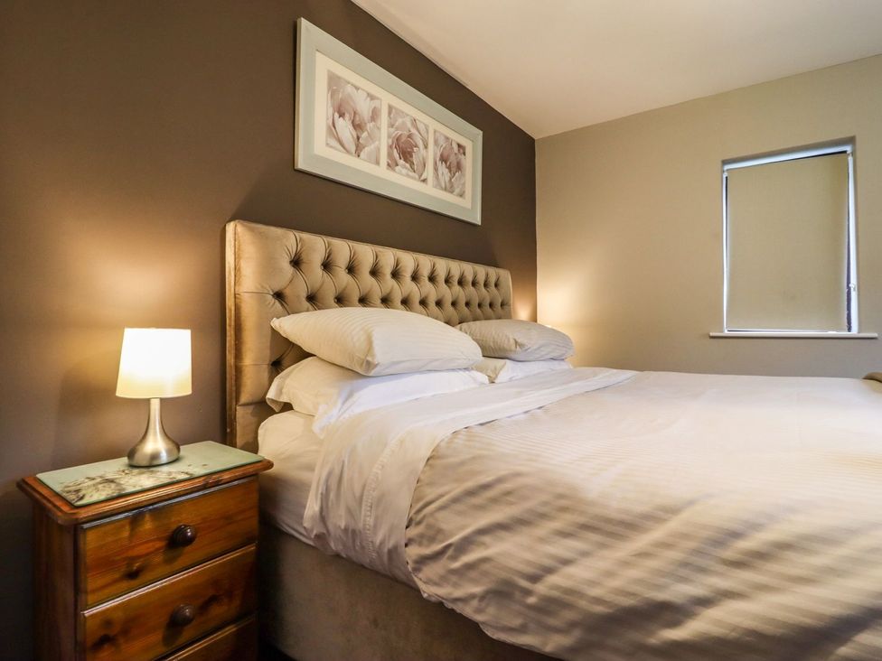 A bedroom with a bed and bedside lamp at Baywood Cottage in Keighley