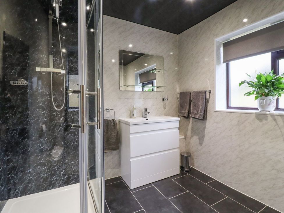 A bathroom with shower, sink, mirror and plant at Baywood Cottage in Keighley