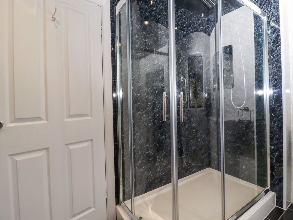 A shower with glass doors at Baywood Cottage in Keighley