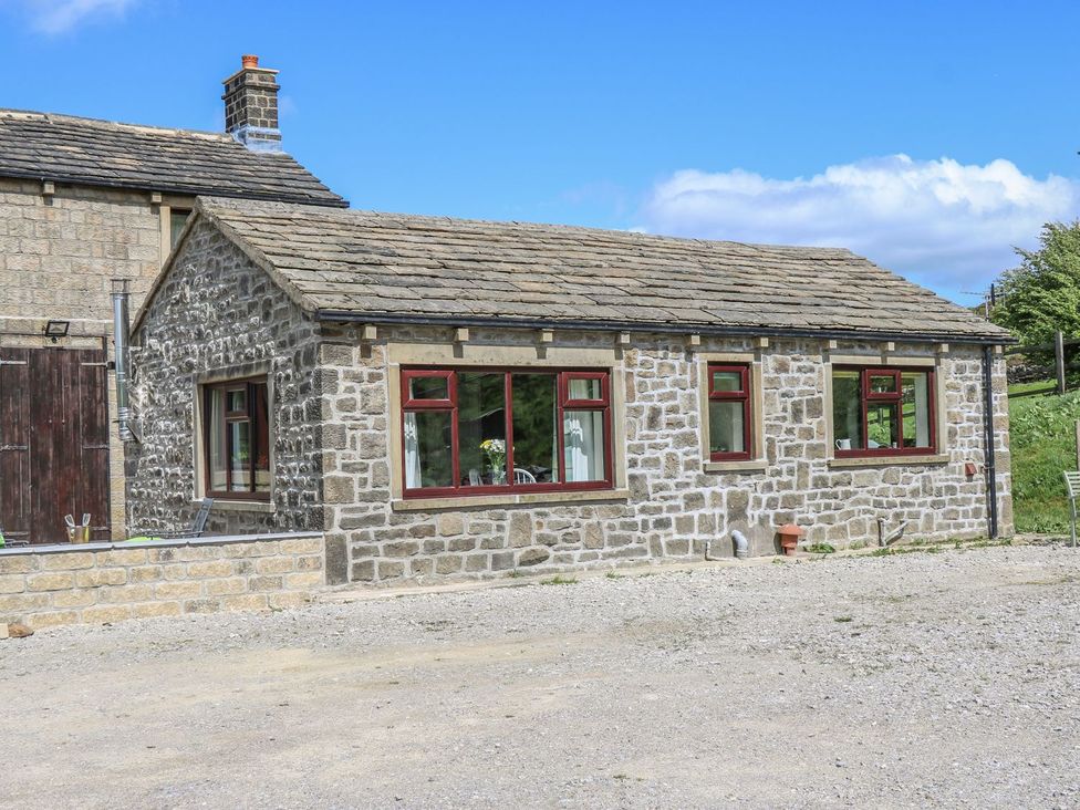 A stone house with multiple windows at Baywood Cottage in Keighley
