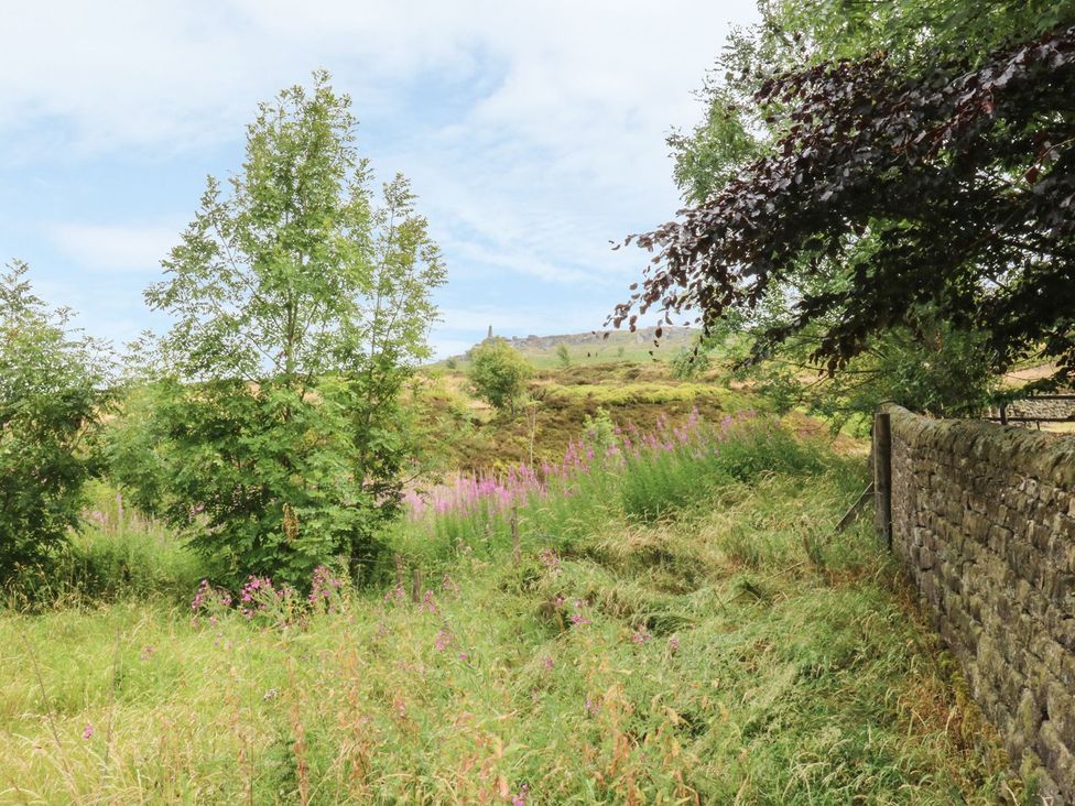 A view of trees and flowers near a stone wall at Baywood Cottage Keighley
