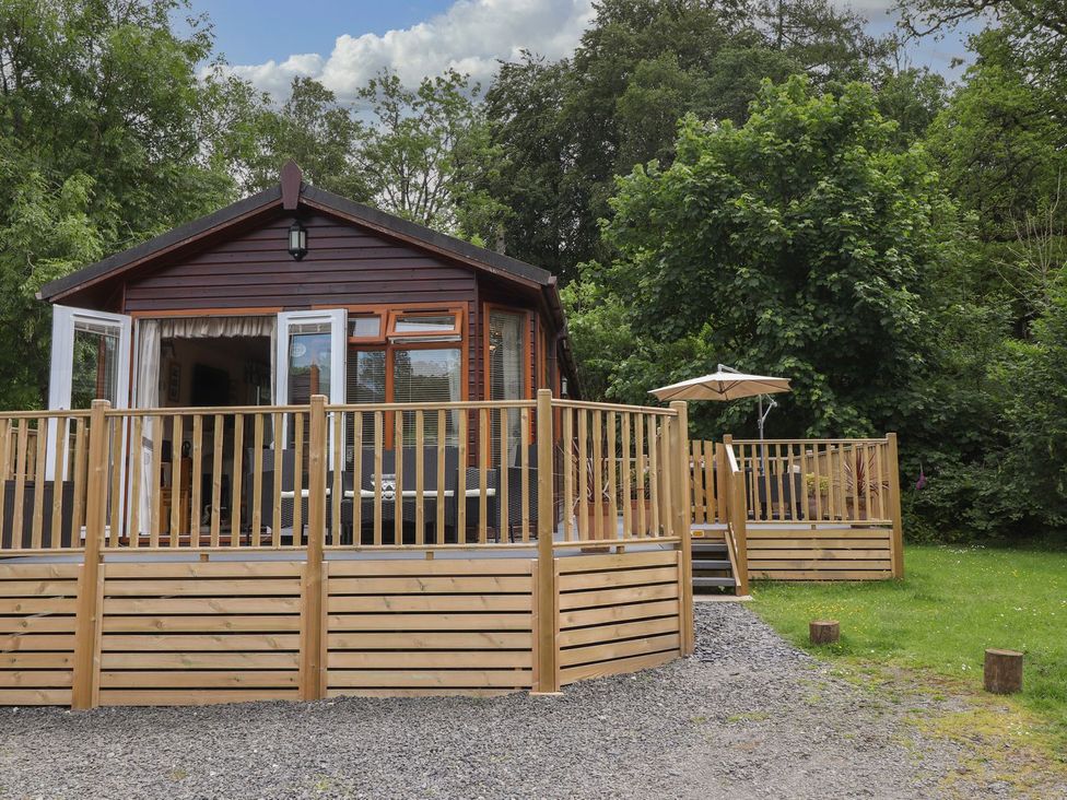 A cabin with decking and an umbrella at Kingfisher Lodge in Windermere