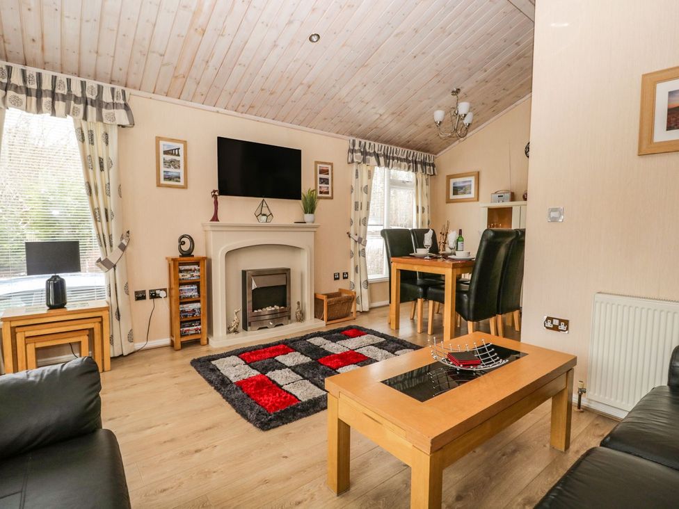 A living room with a coffee table and a television at Kingfisher Lodge Windermere