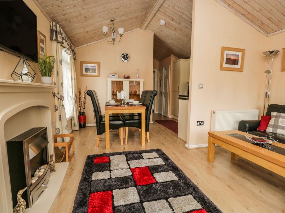 A living room with a dining area and fireplace at Kingfisher Lodge in Windermere