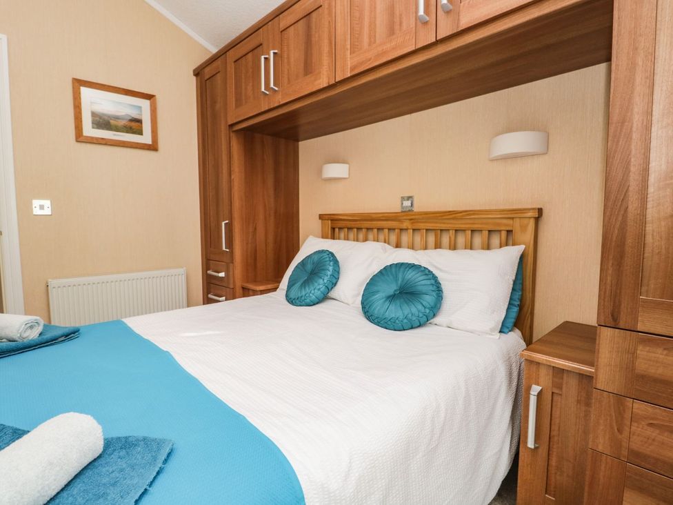 A bedroom with a bed and storage units at Kingfisher Lodge in Windermere
