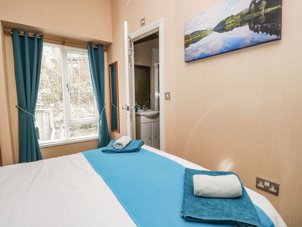 A bedroom with a bed and towels at Kingfisher Lodge in Windermere