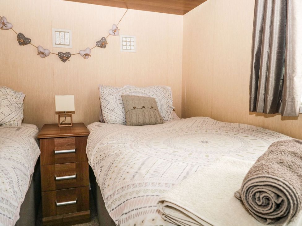 A bedroom with two beds and a bedside table at Kingfisher Lodge in Windermere