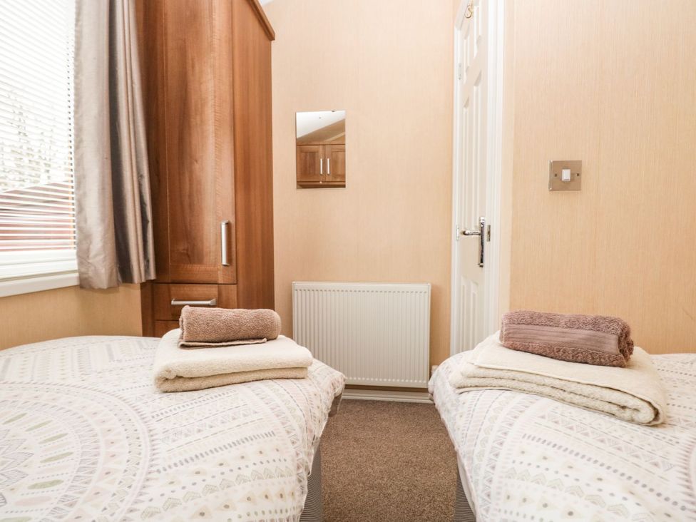 A bedroom with two beds and a wardrobe at Kingfisher Lodge in Windermere