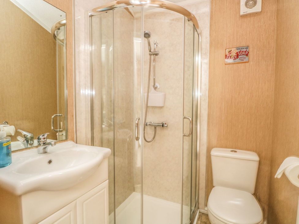 A bathroom with a shower, sink, and toilet at Kingfisher Lodge in Windermere