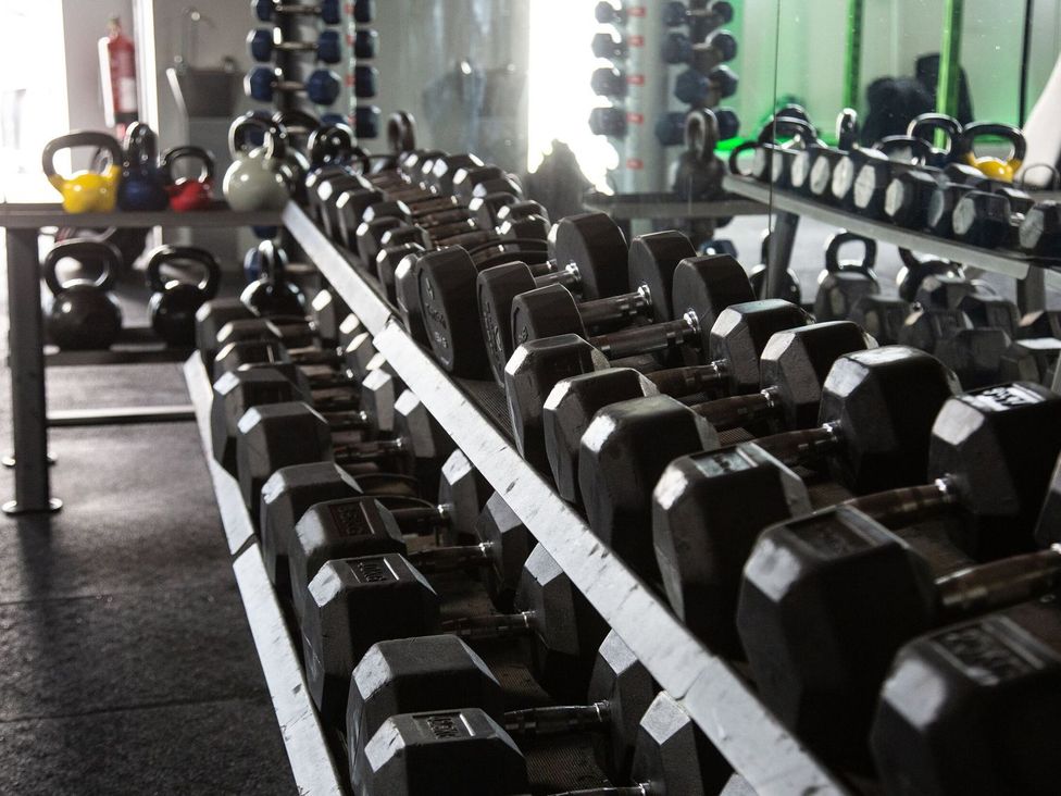 A gym with dumbbells and kettlebells at Kingfisher Lodge in Windermere