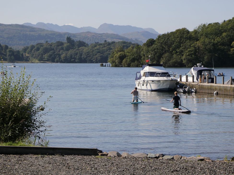 A lake with two paddleboarders and boats at Kingfisher Lodge in Windermere