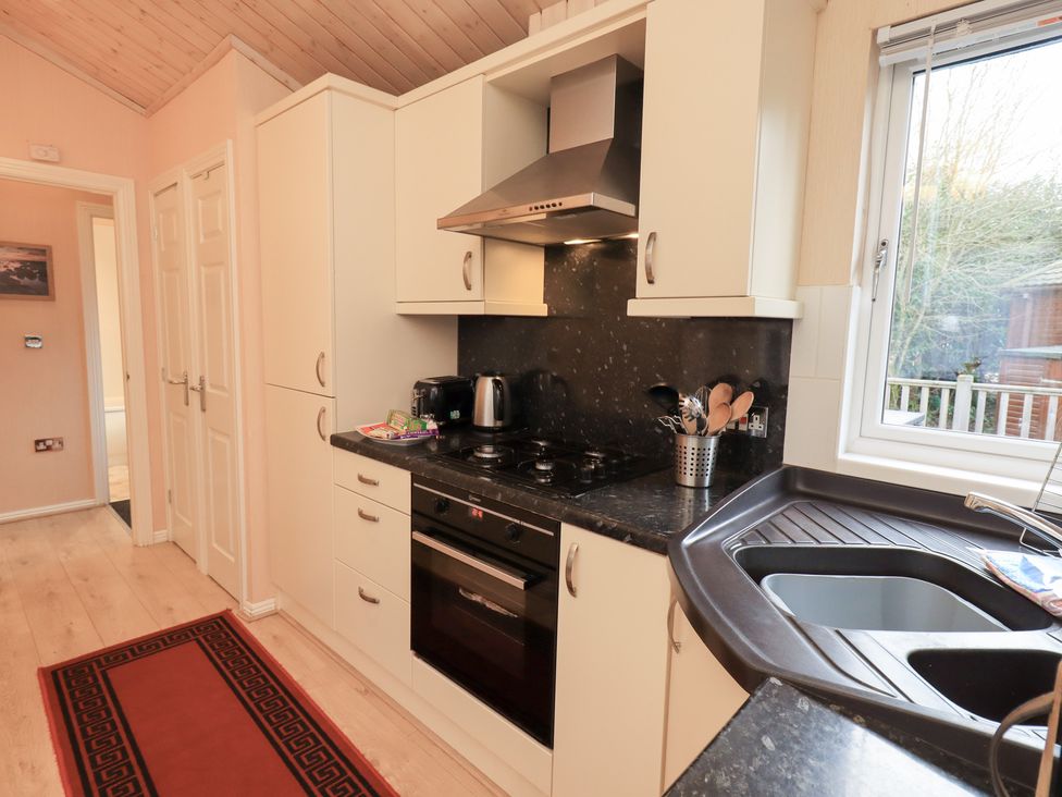 A kitchen with cabinets and appliances at Kingfisher Lodge Grasmere 33, White Cross Bay near Windermere