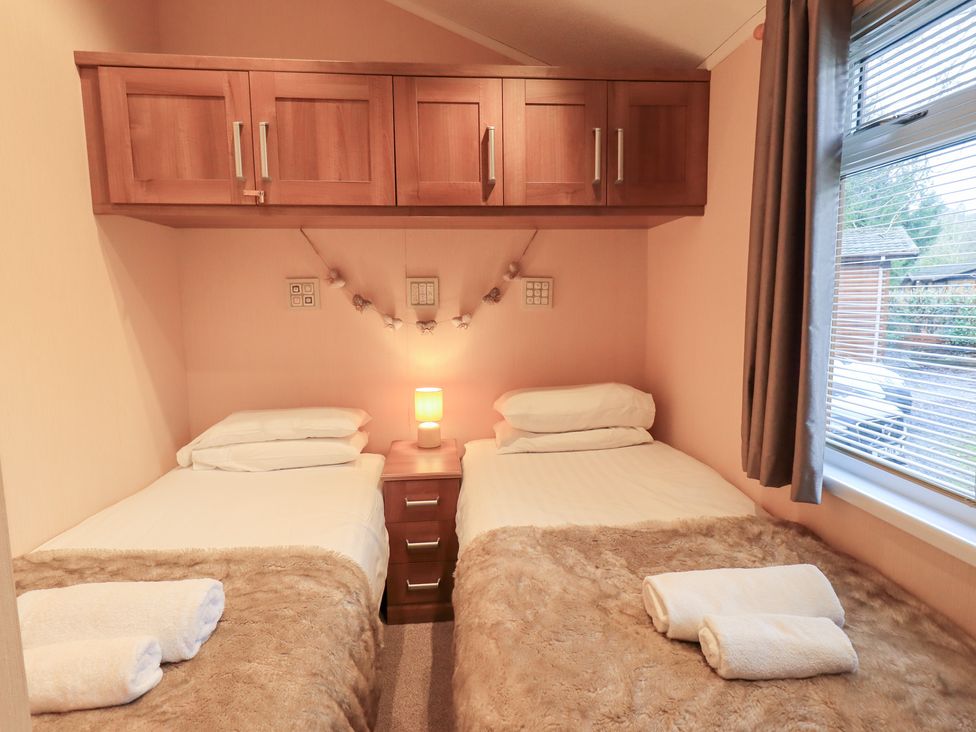 A bedroom with twin beds and a lamp at Kingfisher Lodge Grasmere 33, White Cross Bay near Windermere