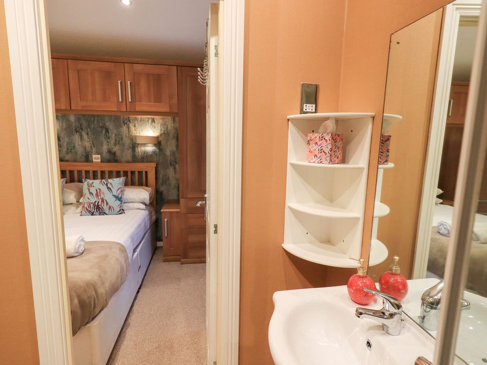 A bedroom with a bed and sink at Kingfisher Lodge Grasmere 33, White Cross Bay near Windermere