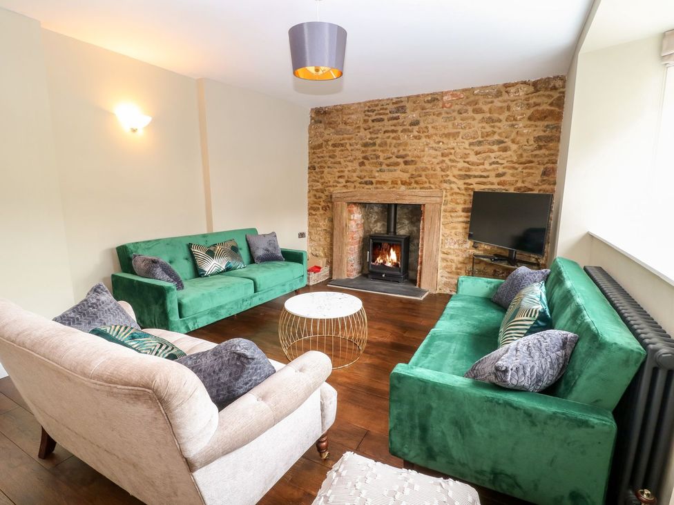 A living room with green sofas and a fireplace at The Old Bakery in Banbury