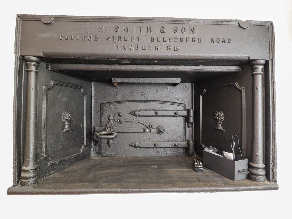 A fireplace with a metal door and remote control at The Old Bakery in Banbury