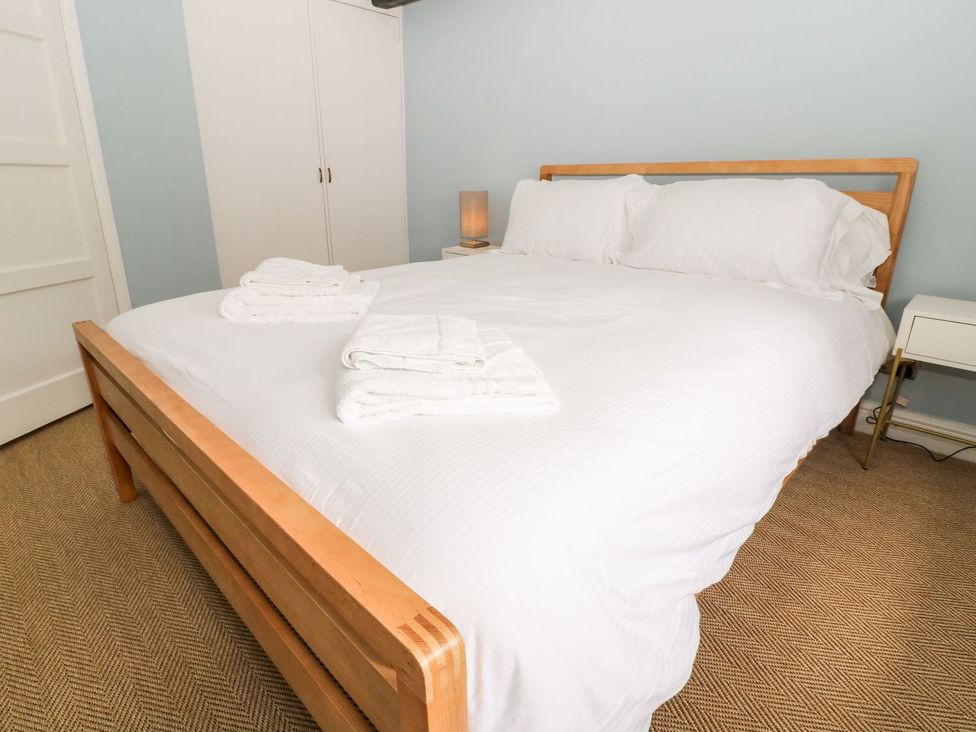 A bedroom with a bed, towels, and bedside lamp at The Old Bakery in Banbury