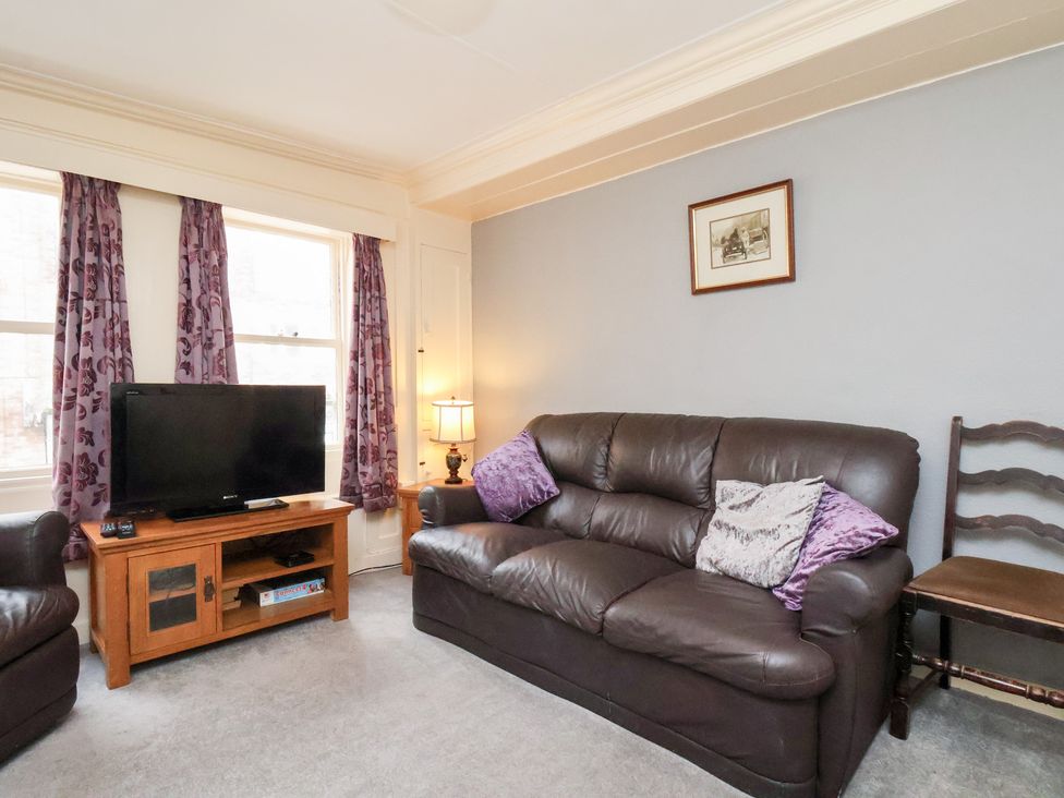 A living room with a television and sofa at Stowaway Cottage in Whitby
