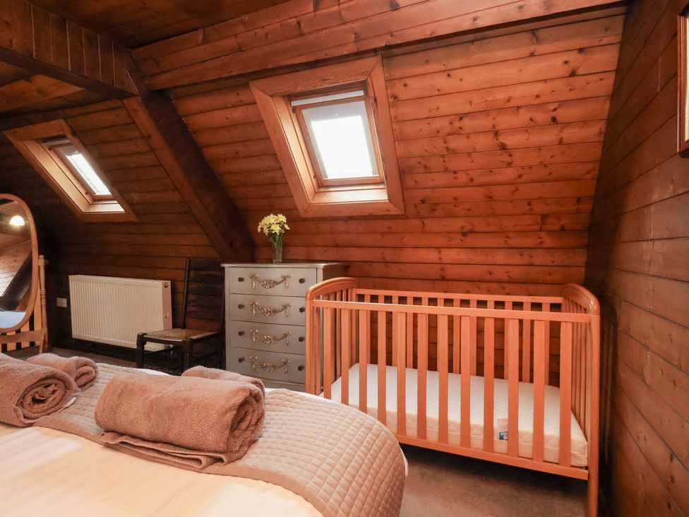 A bedroom with a crib and a dresser at Stowaway Cottage in Whitby