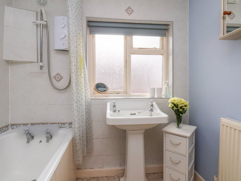 A bathroom with a bathtub and washbasin at Stowaway Cottage in Whitby