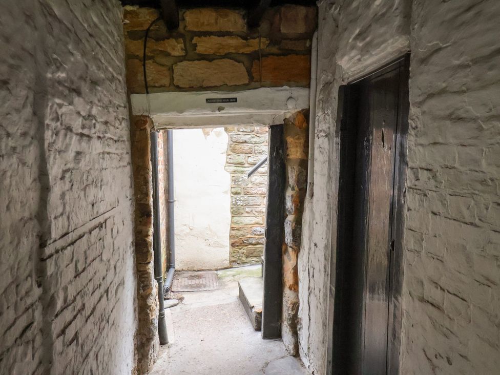 A hallway with stone walls and doors leading to rooms at Stowaway Cottage Whitby