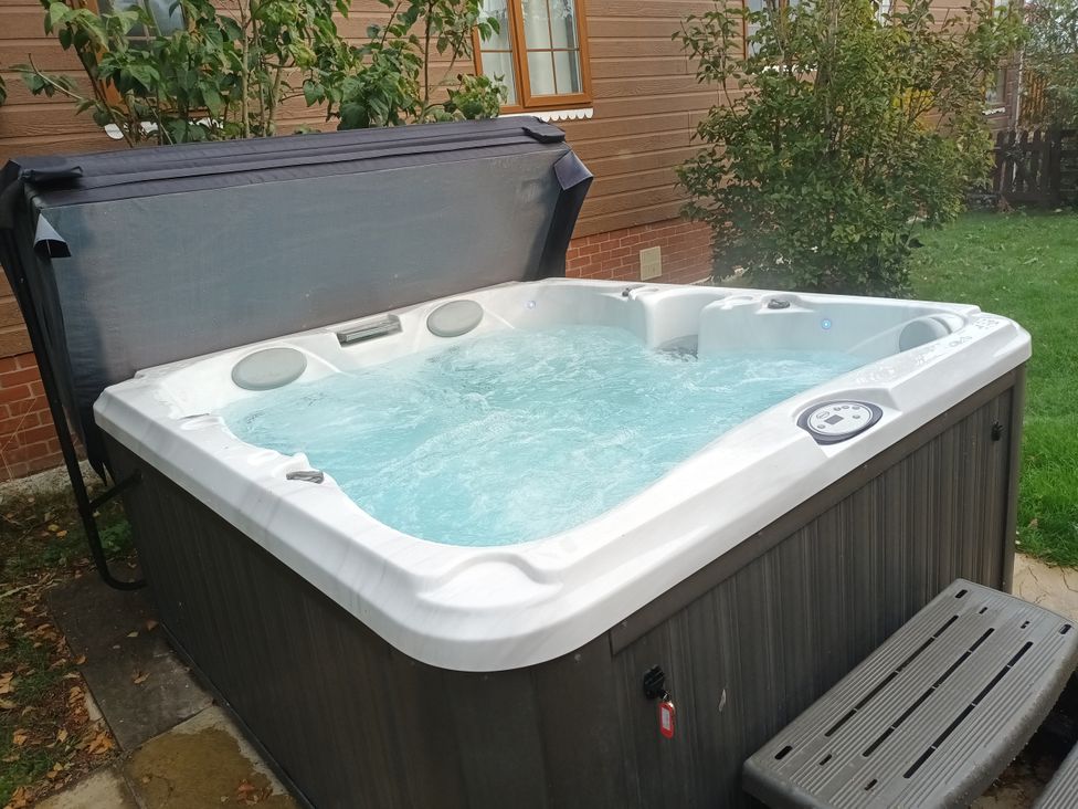A hot tub with a cover and steps at Fern Lodge Stowmarket