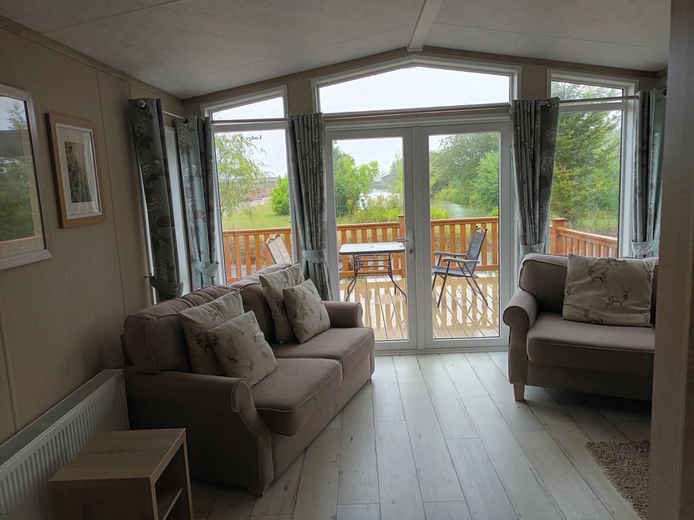 A living room with sofas and a sliding door leading to a deck at Fern Lodge in Stowmarket