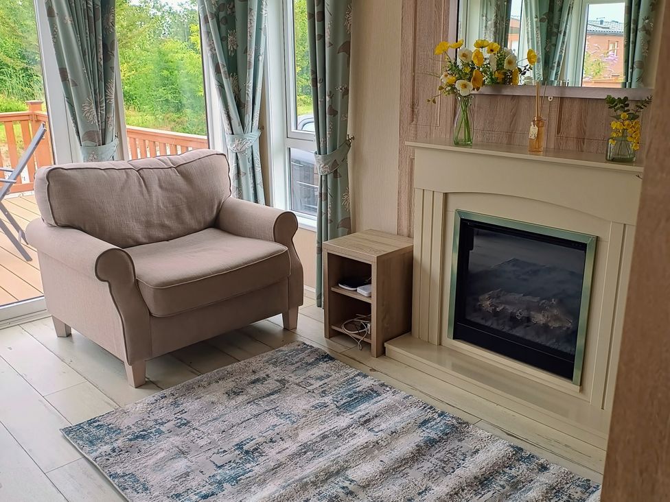 A living room with an armchair and fireplace at Fern Lodge in Stowmarket