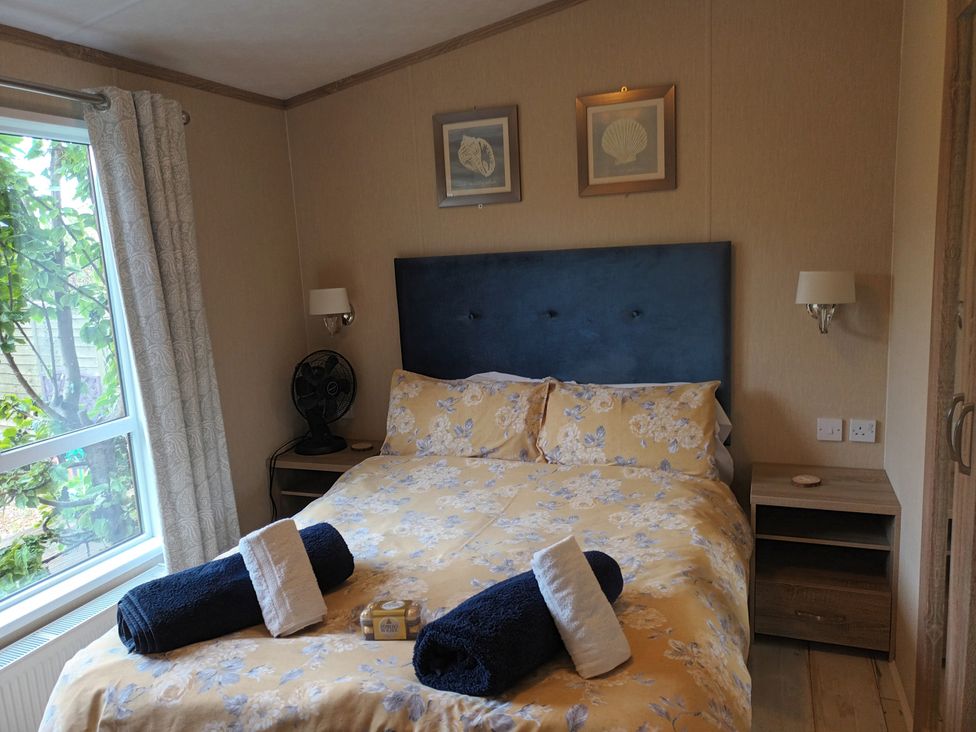 A bedroom with a bed and bedside table at Fern Lodge in Stowmarket