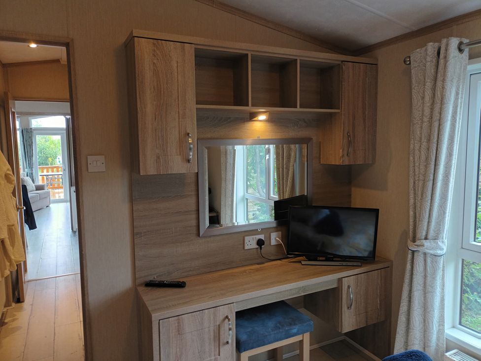 A bedroom with a desk and television at Fern Lodge in Stowmarket