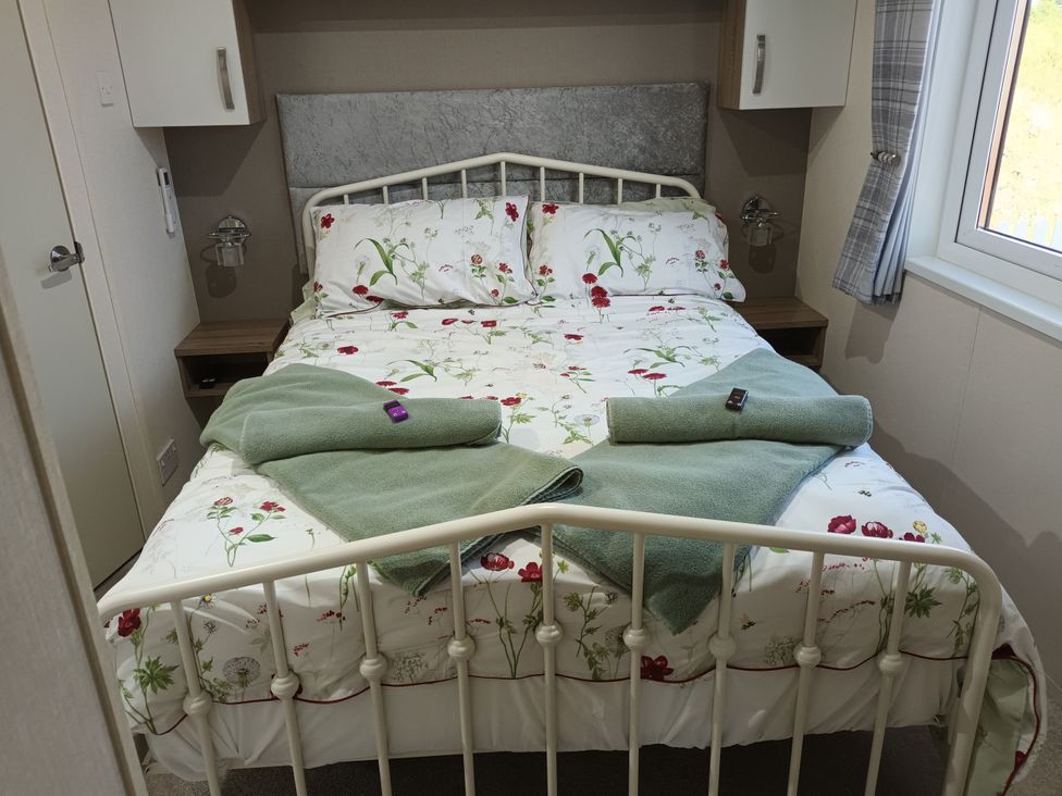 A bed with floral sheets and towels in a bedroom at Fern Lodge Stowmarket