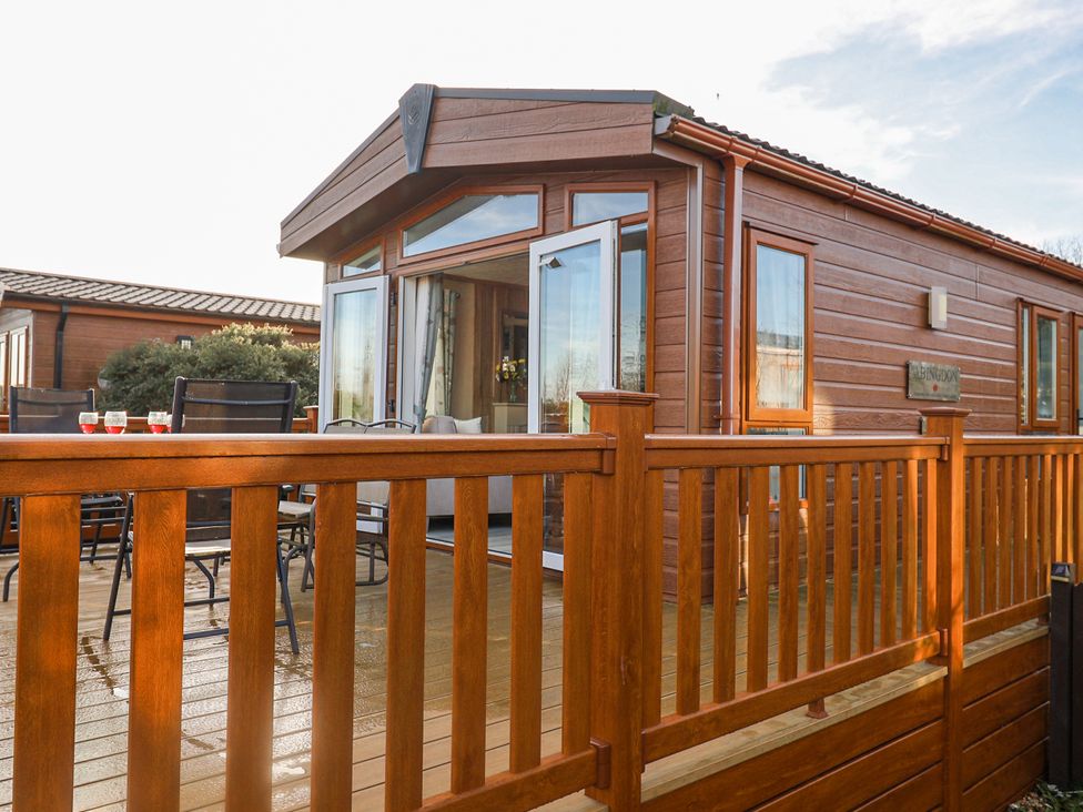A wooden lodge with a deck in front at Fern Lodge in Stonham Aspal